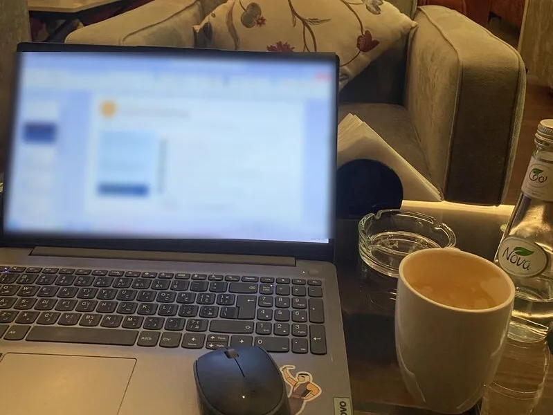 حاسوب محمول وفنجان قهوة على طاولة في مقهى، في إشارة إلى العمل اليومي للمدير في تنظيم الأولويات والتخطيط
